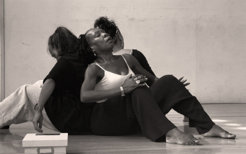 image of three black women sitting back to back on the floor