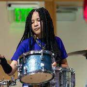 A young african american girl playing drums