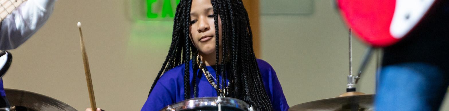 Image of a young African American Girl playing drums