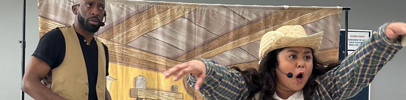 A latina woman works the crowd while a black man grimaces in a production of "Aesop's Fables."