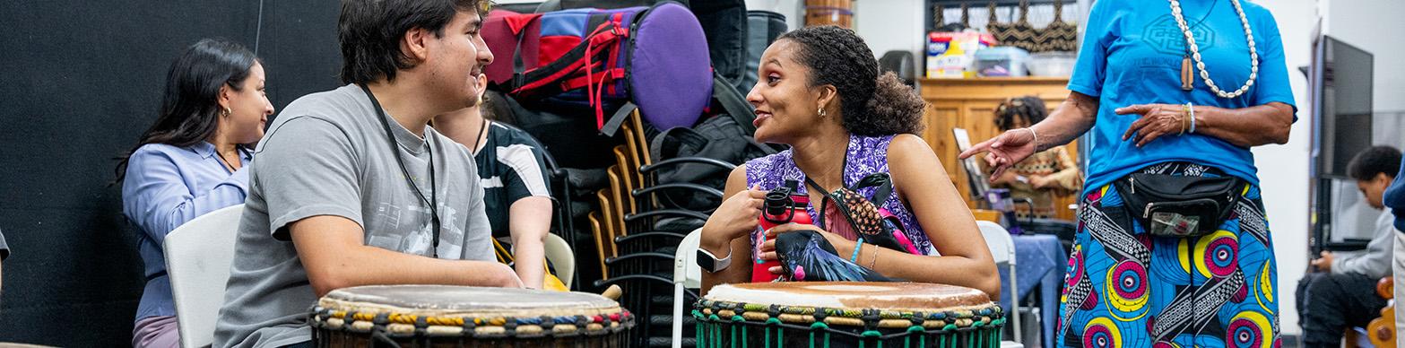 Two Interns chat over a pair of drums