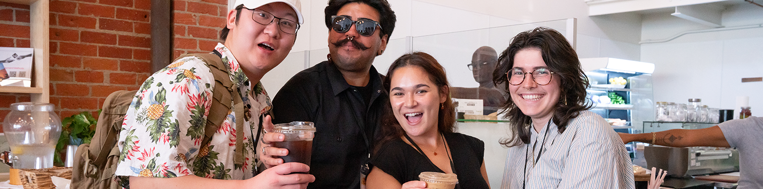 Four interns pose with coffees