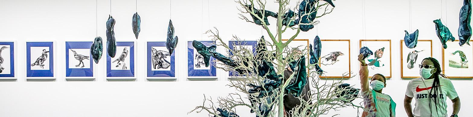 Individuals in masks interact with a butterfly themed installation