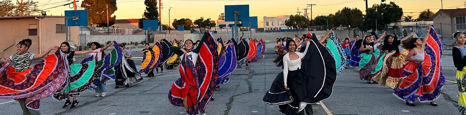 Young women dance in traditional Mexican dress.