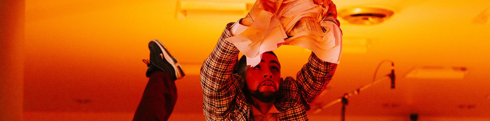 Man holds an arabesque while listing a crumpled piece of paper above his head