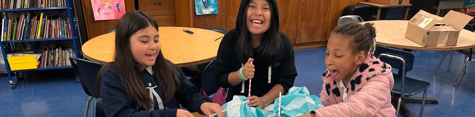 Three young girls laugh and craft