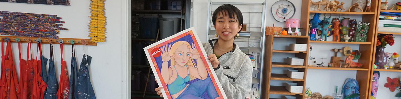 Young Asian girl holds up Barbie poster