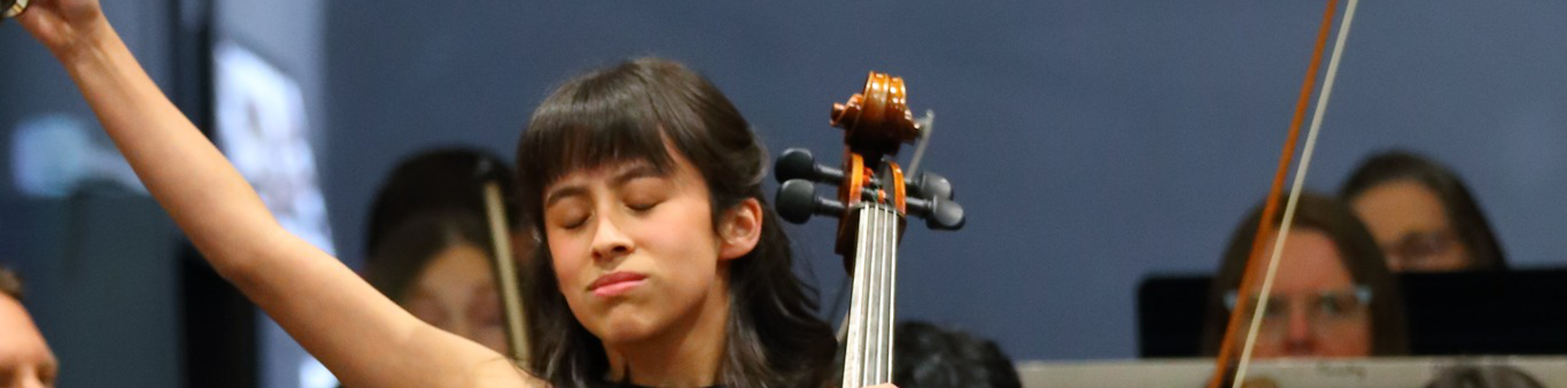 Young girl plays cello with eyes closed