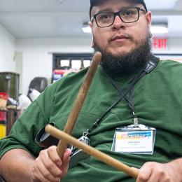 Male intern holds drum sticks, ready to play