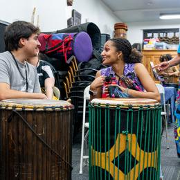 Two interns chat over a pair of drums